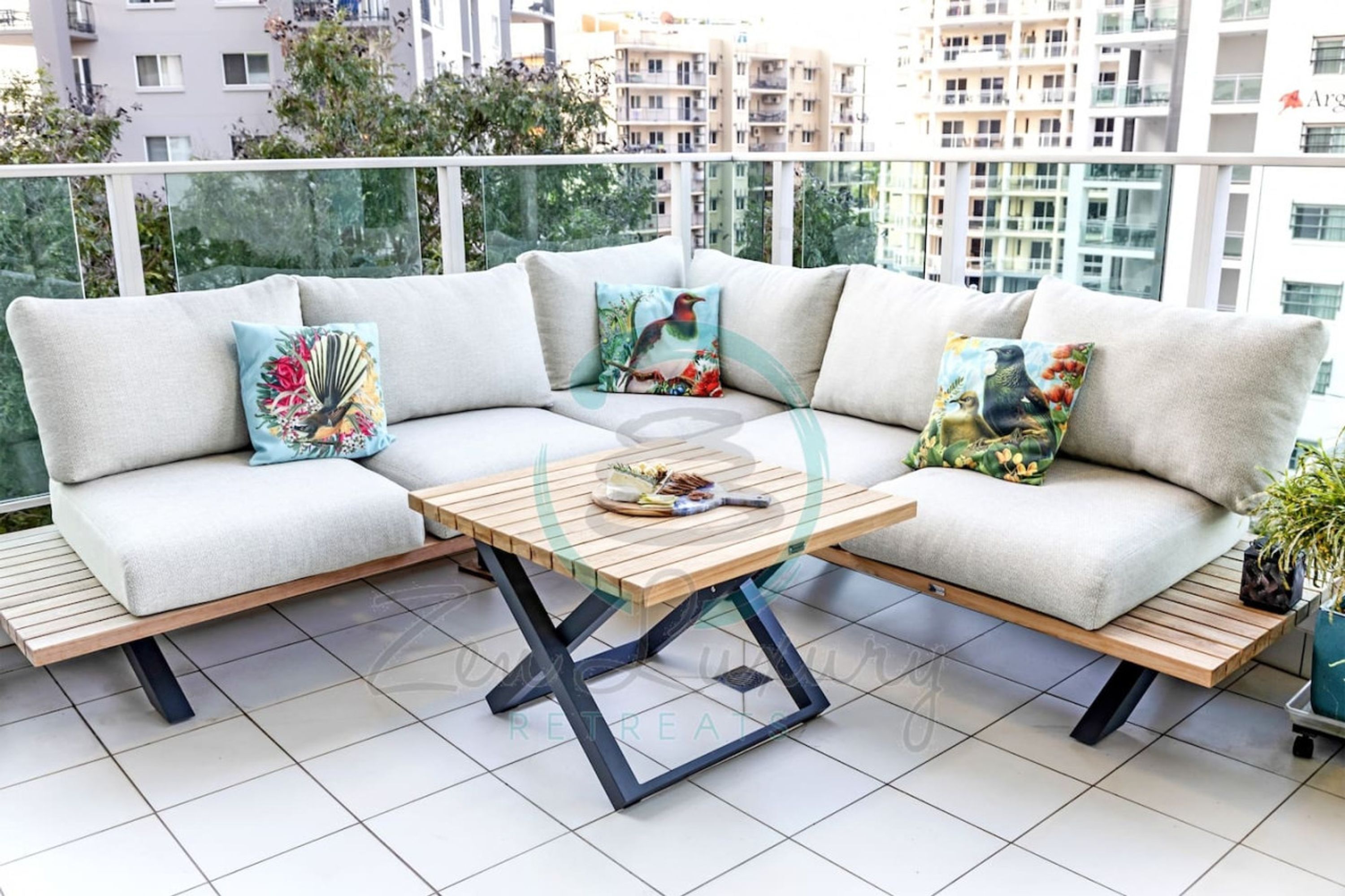 A modern outdoor seating area with a sofa and a wooden table, set against a cityscape view.