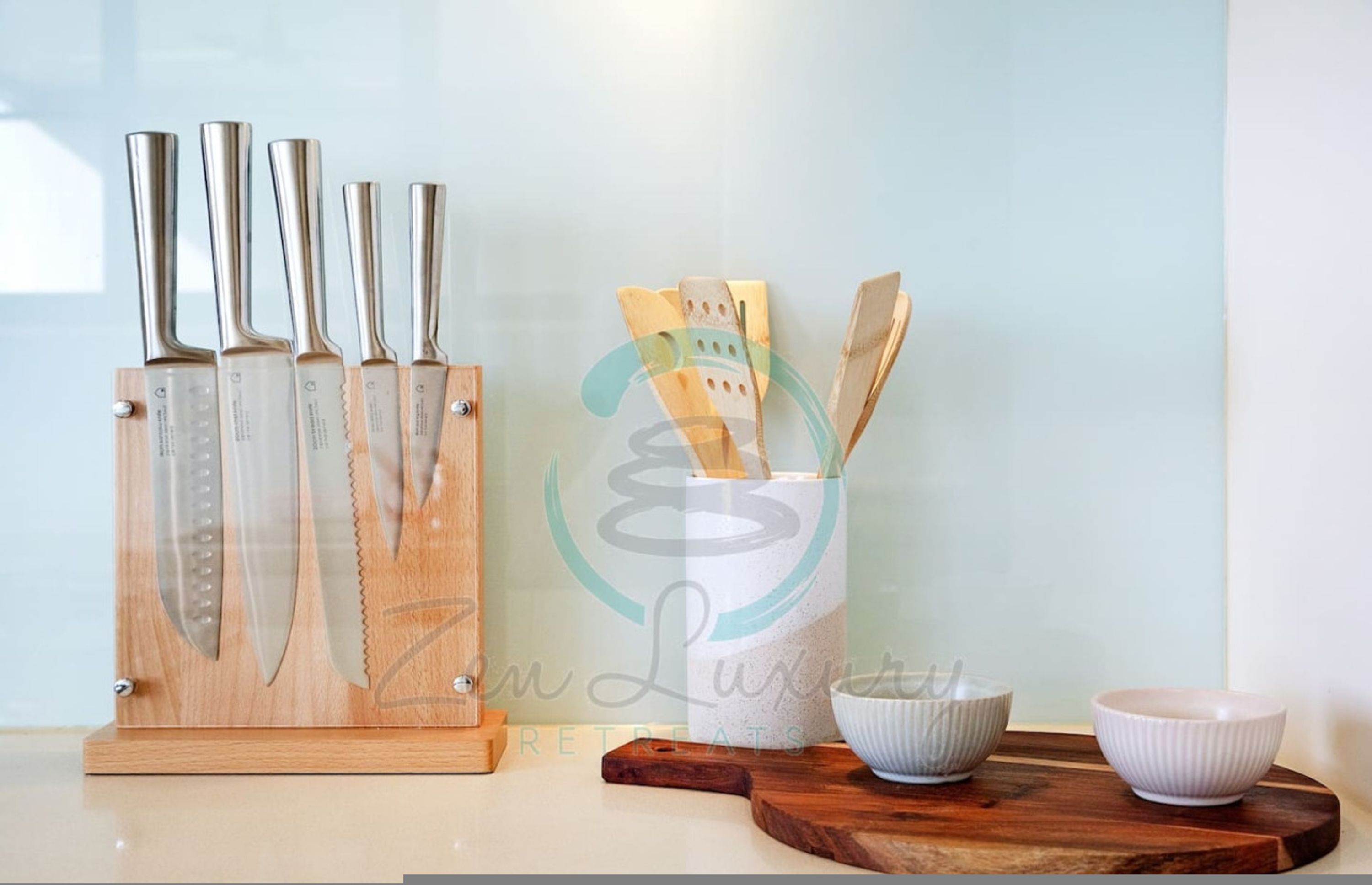 Una encimera de cocina con un bloque de cuchillos, utensilios de madera y dos cuencos.