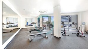A modern gym with cardio machines, weight benches, and a large mirror. - Seaview Haven Ocean Vistas Gym Pool Parking (Darwin)