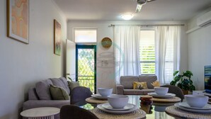 Ein modernes Wohnzimmer mit einem Glastisch, zwei Sofas und einem Fernseher.