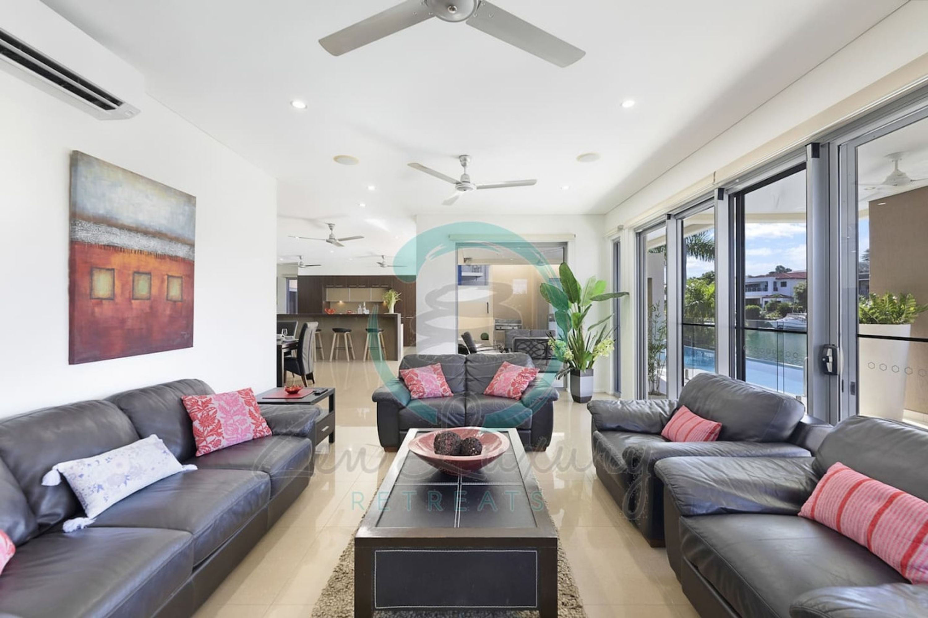 A modern living room with leather sofas, a coffee table, and a painting on the wall.