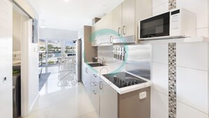 Una cocina moderna con electrodomésticos de acero inoxidable, un microondas y un salpicadero de azulejos.