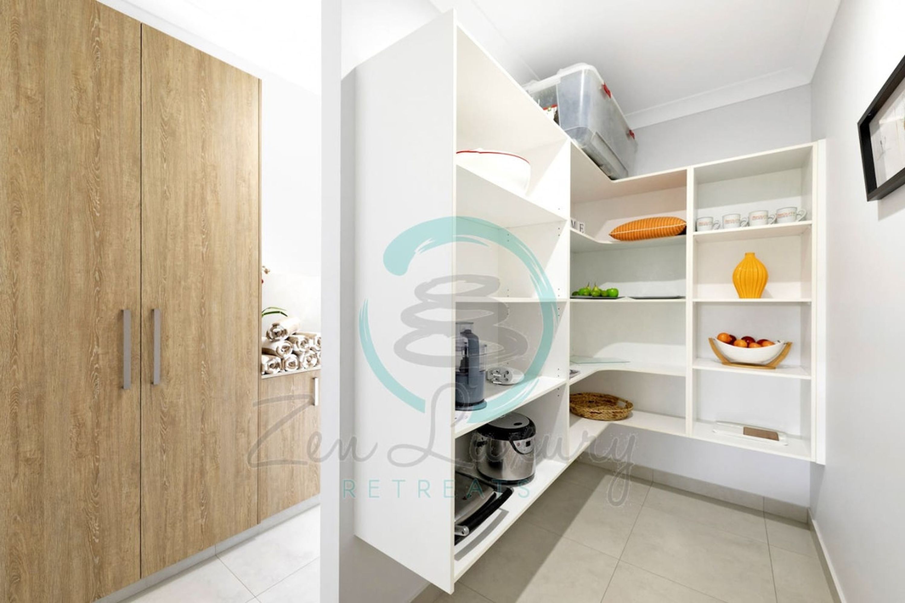 Una cocina moderna con armarios blancos, un mueble de madera y una estantería empotrada con varios objetos.
