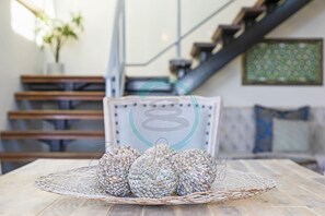A dining table with a woven basket containing several spherical objects, a chair, and a staircase in the background. - Pinnacle Penthouse Ambience Views Pool Gym (Darwin)