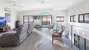 A spacious living area with a sofa, chairs, and a balcony with a railing. - Pinnacle Penthouse Ambience Views Pool Gym (Darwin)