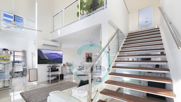 Ein modernes Wohnzimmer mit Treppe, Flachbildfernseher und Glastrennwand.