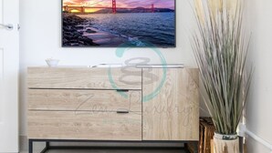 Ein modernes Wohnzimmer mit einem großen Fernseher an der Wand, der einen schönen Sonnenuntergang über einer Brücke zeigt.