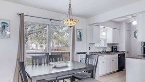 A modern kitchen with white cabinets, a dining table with chairs, and a pendant light. - Adventure House #17 (Rockport)