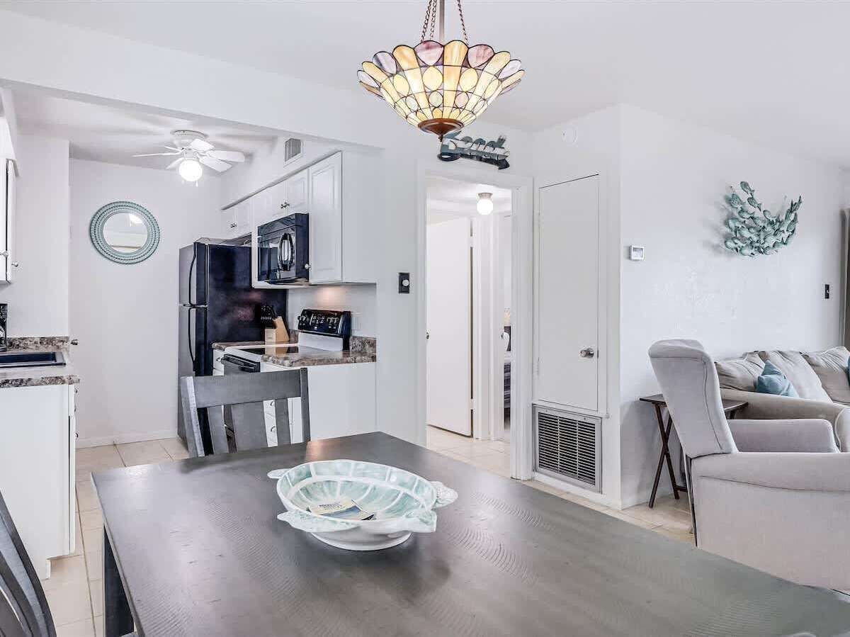 A modern kitchen with a dining table, a ceiling fan, and a decorative light fixture.