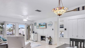A spacious living room with a fireplace, a dining area with a table and chairs, and a large window offering a view of the outdoors. - Adventure House #17 (Rockport)