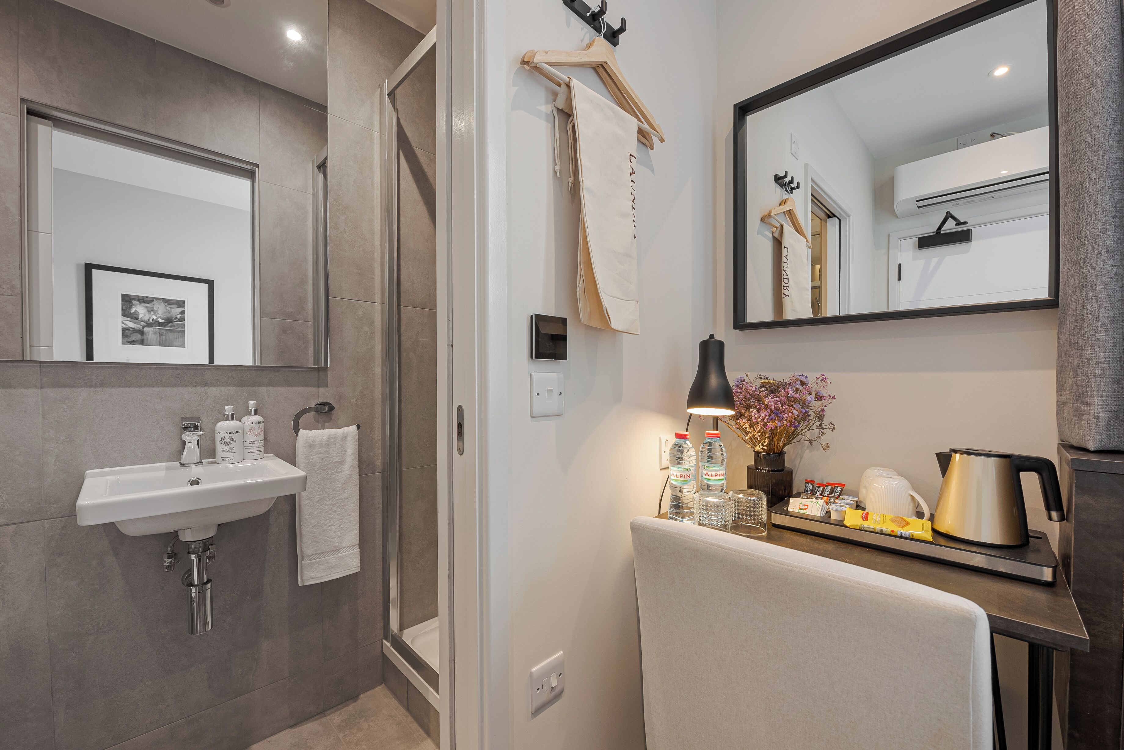 A modern bathroom with a sink, mirror, towel rack, and a tray with toiletries.