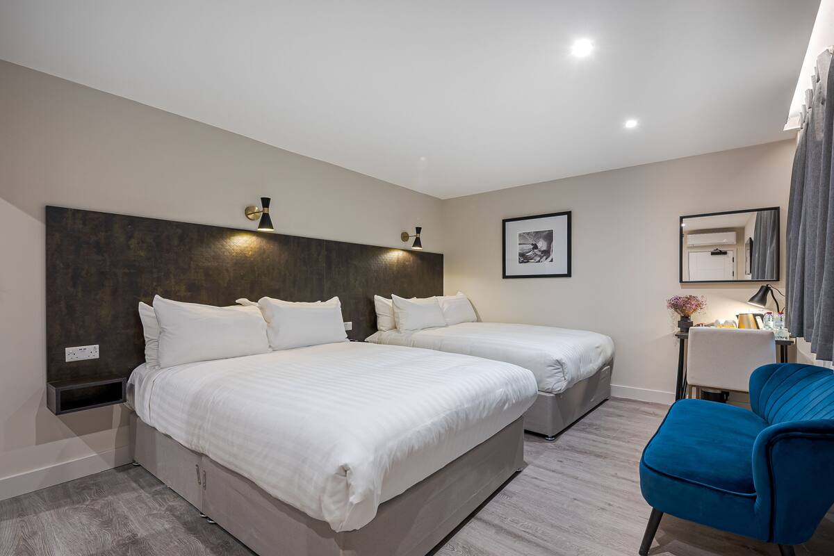 Une chambre d’hôtel avec deux lits, un bureau, une chaise et un grand miroir.