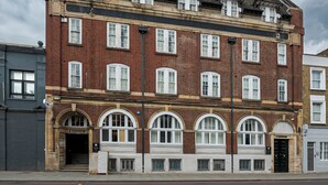 A multi-story brick building with arched windows and a flat roof. - King's Cross Express Inn (London)