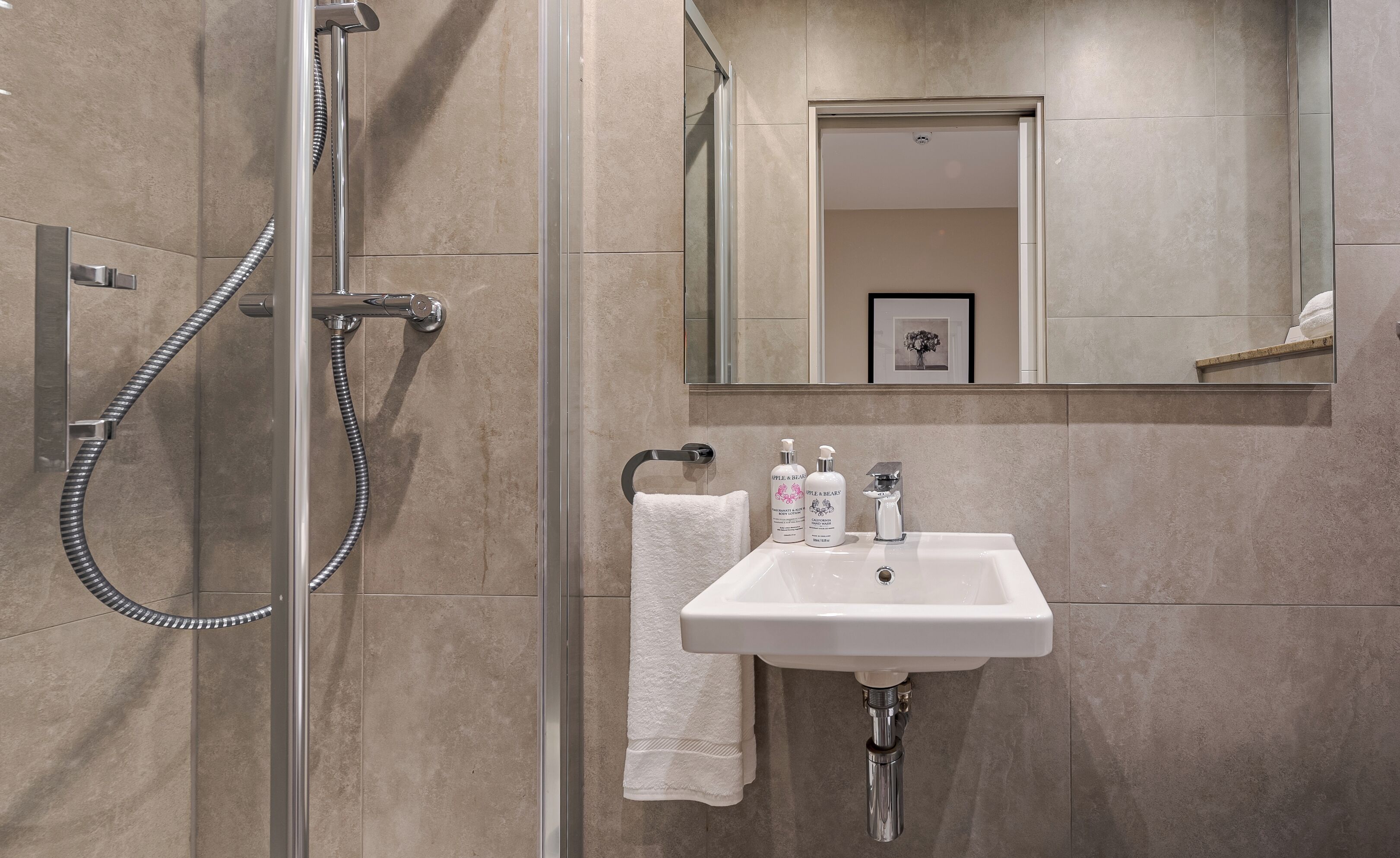 A modern bathroom with a glass-enclosed shower, a white sink, and a mirror above it.