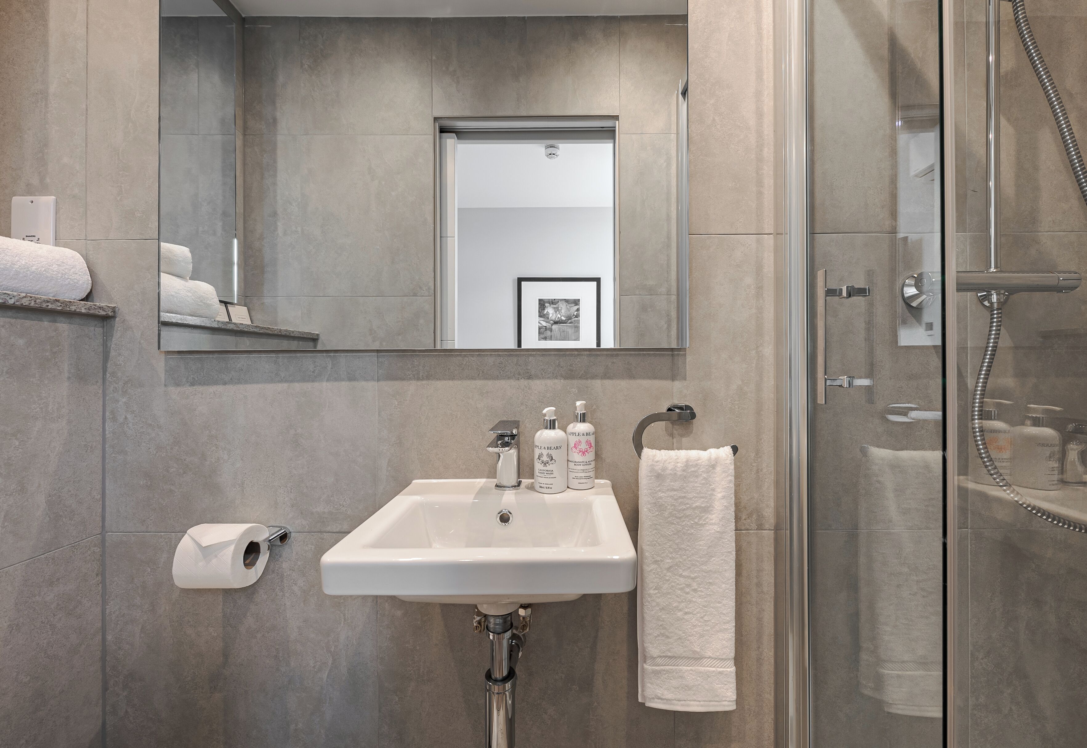 Un bagno moderno con lavandino, carta igienica e doccia.