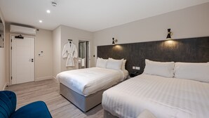 A hotel room with two beds, a wardrobe, a mirror, and a blue chair. - King's Cross Express Inn (London)