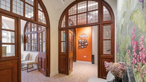 An interior with arched wooden doors, a seating area, and a wall with framed pictures. - King's Cross Express Inn (London)