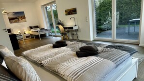 Une chambre moderne avec un grand lit, un bureau et une vue sur l’extérieur.