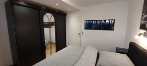 Une chambre à coucher avec un lit, une armoire, une porte et un tableau accroché au mur.