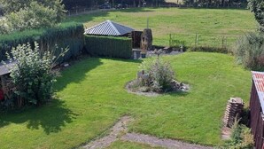 Ein ländliches Anwesen mit eingezäuntem Garten, einer kleinen Werkstatt und einem Gartenbereich.
