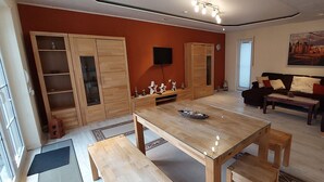 Ein Wohnzimmer mit Holztisch, einer Couch und einem an der Wand befestigten Fernseher.