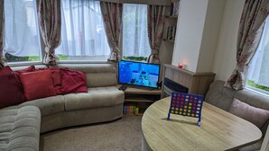 Una sala de estar acogedora con un sofá, un televisor y una mesa con un puzle de puntos.