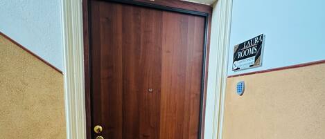 A wooden door with a doormat labeled 'Laura Room' and a sign above it reading 'Laura Rooms.'