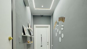 Un pasillo con una puerta blanca, un estante con libros y una pared con espejos circulares y el texto 'WELCOME HOME'.