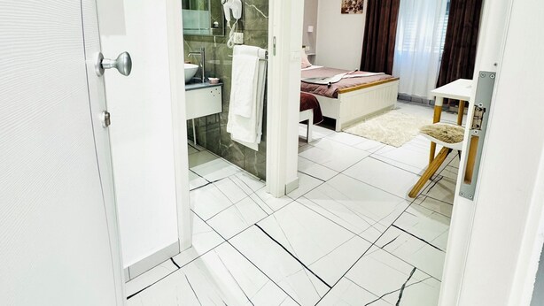 Un baño moderno con cabina de ducha de vidrio, un lavamanos blanco y un perchero para toallas.