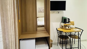 Una habitación con cama, televisor, mesa con sillas y un armario de madera.
