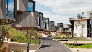A modern residential complex with unique architectural design, featuring multiple levels and balconies, and a central pathway.