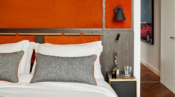 Una habitación de hotel con una cama, una mesita de noche, una lámpara y un cuadro en la pared.