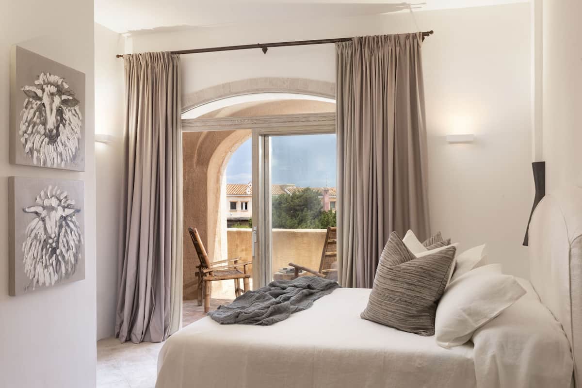 Ein Schlafzimmer mit einem großen Bett, Blick durch eine Glastür und zwei Kunstwerken an der Wand.