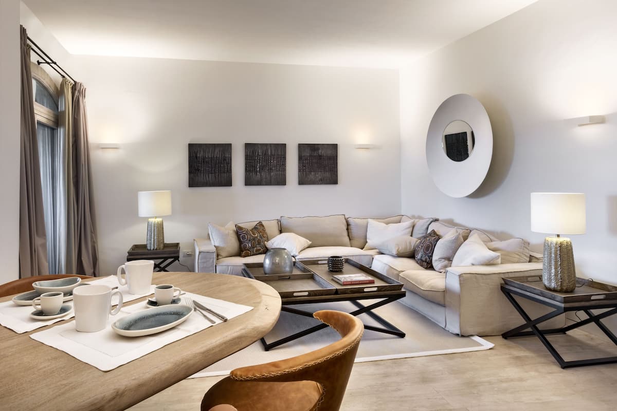 Ein modernes Wohnzimmer mit Sofa, Couchtisch und Esstisch, gedeckt mit Tellern, Tassen und einer Vase.