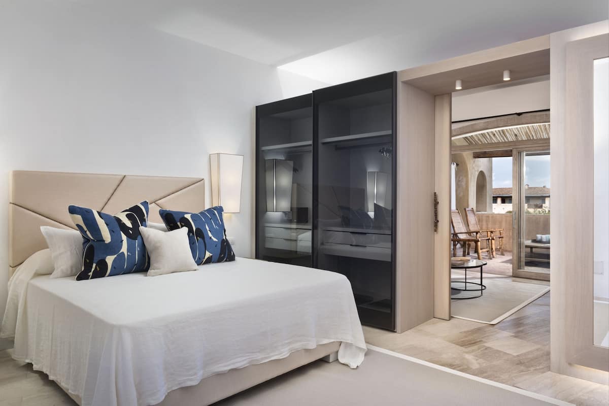Ein modernes Schlafzimmer mit einem großen Bett, einem begehbaren Kleiderschrank und Blick auf die Terrassenanlage.