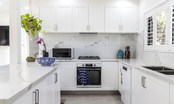 A modern kitchen with white cabinets, a microwave, a gas stove, and a dishwasher.