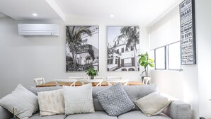 Un salon moderne avec un canapé gris, une table à manger en bois et deux tableaux encadrés en noir et blanc accrochés au mur.