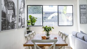 Un coin repas avec une table en bois, des chaises blanches et une plante en pot.