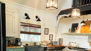 Una cocina con una isla central, taburetes de madera, una cafetera y una estufa.
