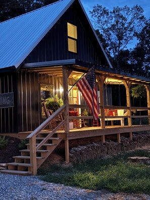 A wooden cabin with a porch, a staircase, and an American flag. - Flat Creek Cabin at Riverbend Farm in Evening Shade Arkansas (Poughkeepsie)