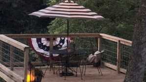 Una terraza con una mesa y sillas, una bandera estadounidense colgada y luces de cadena.