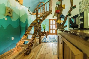 A wooden staircase with a rustic design, a dining area with a table and chairs, and a kitchen area with a stove and cabinets.