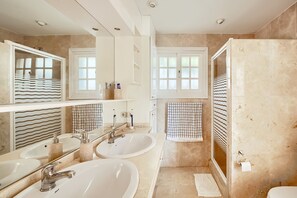 Bathroom features two sinks, a large mirror, and a shower area with a glass door.