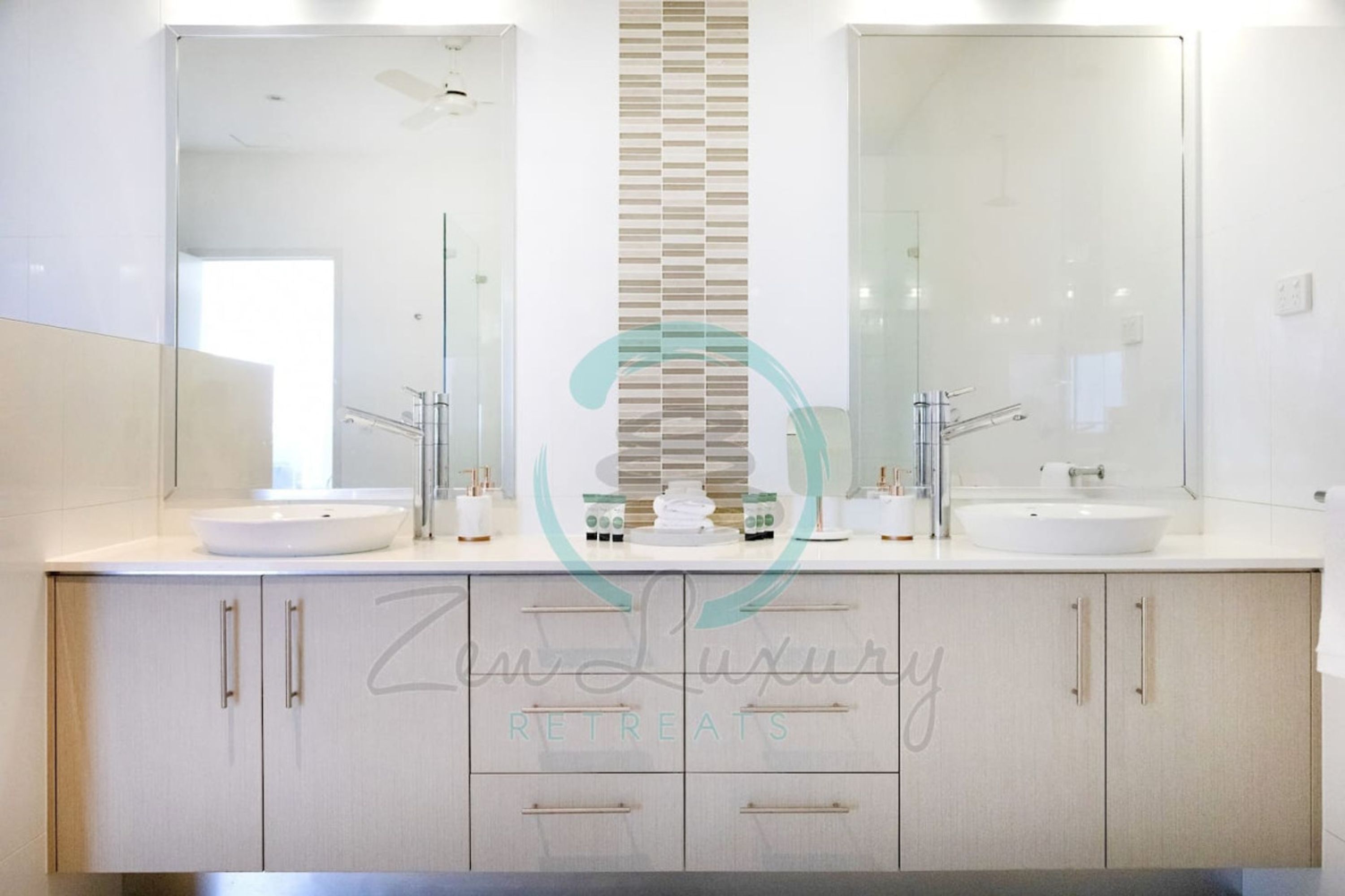 A modern bathroom with two sinks, a large mirror, and a decorative wall panel.