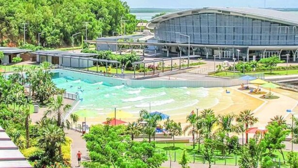A modern hotel with a large swimming pool, a beach area, and lush greenery. - Zen Ocean View Ph Spacious Living Pool Parking (Darwin)