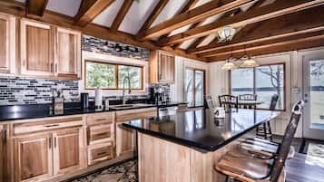 A kitchen with wooden cabinets, a black countertop, and a large island with seating.