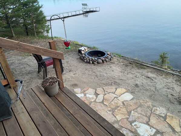Una terraza de madera con un hogar de piedra y una maceta colgante.