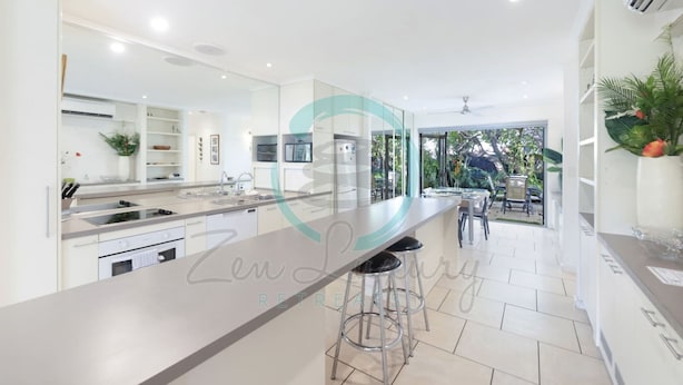 A modern kitchen with a large island, built-in appliances, and a view to an outdoor patio area. - Zen Treetops Private Pool Outdoor Dining (Larrakeyah)