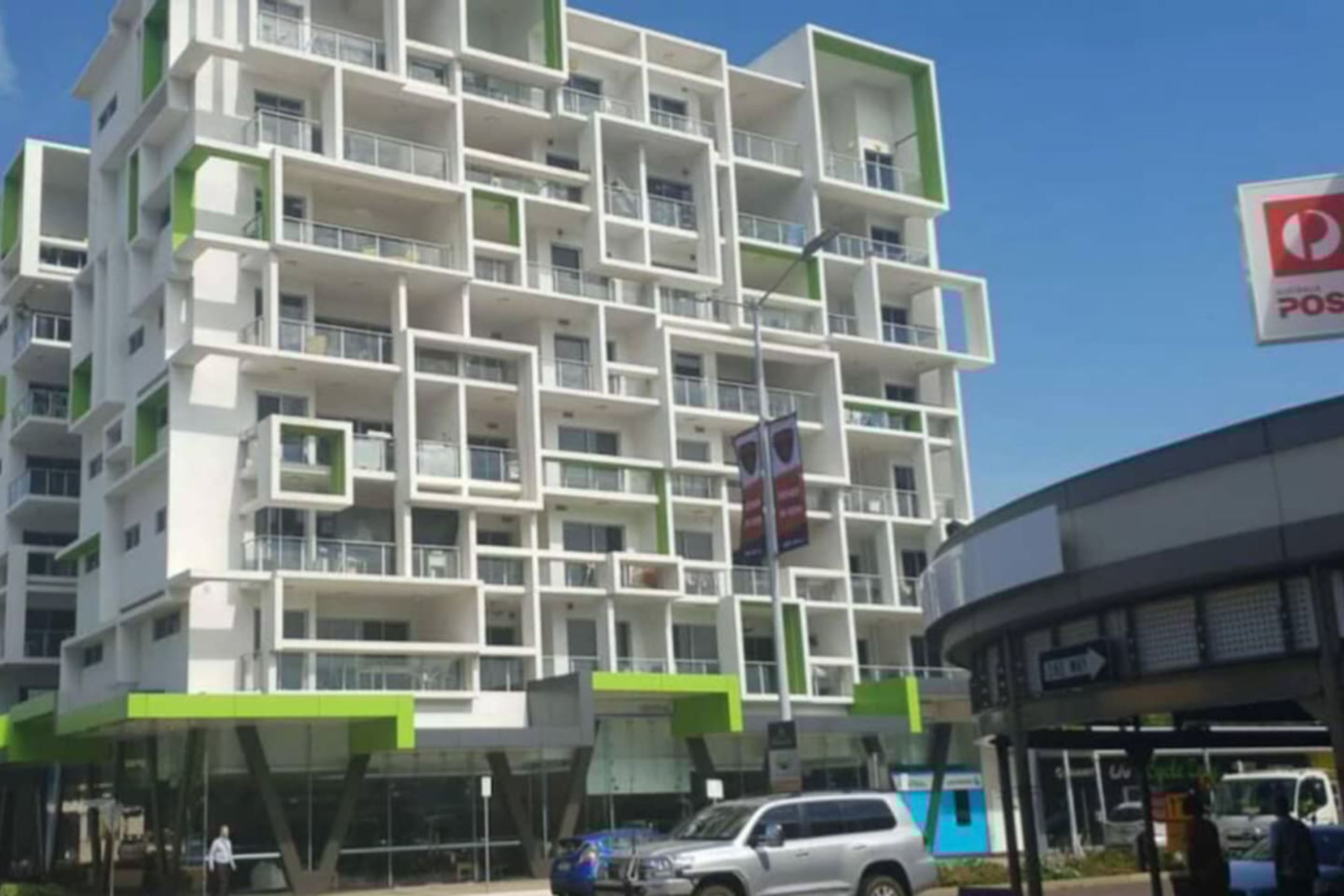 Un immeuble à plusieurs étages doté d’une architecture moderne, avec des balcons et une touche de verdure bien visible sur les niveaux inférieurs.