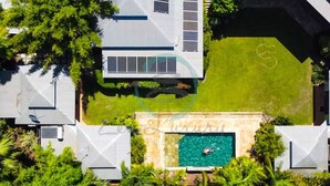 Eine Vogelperspektive auf ein modernes Haus mit Swimmingpool, Solaranlage und üppiger Bepflanzung.